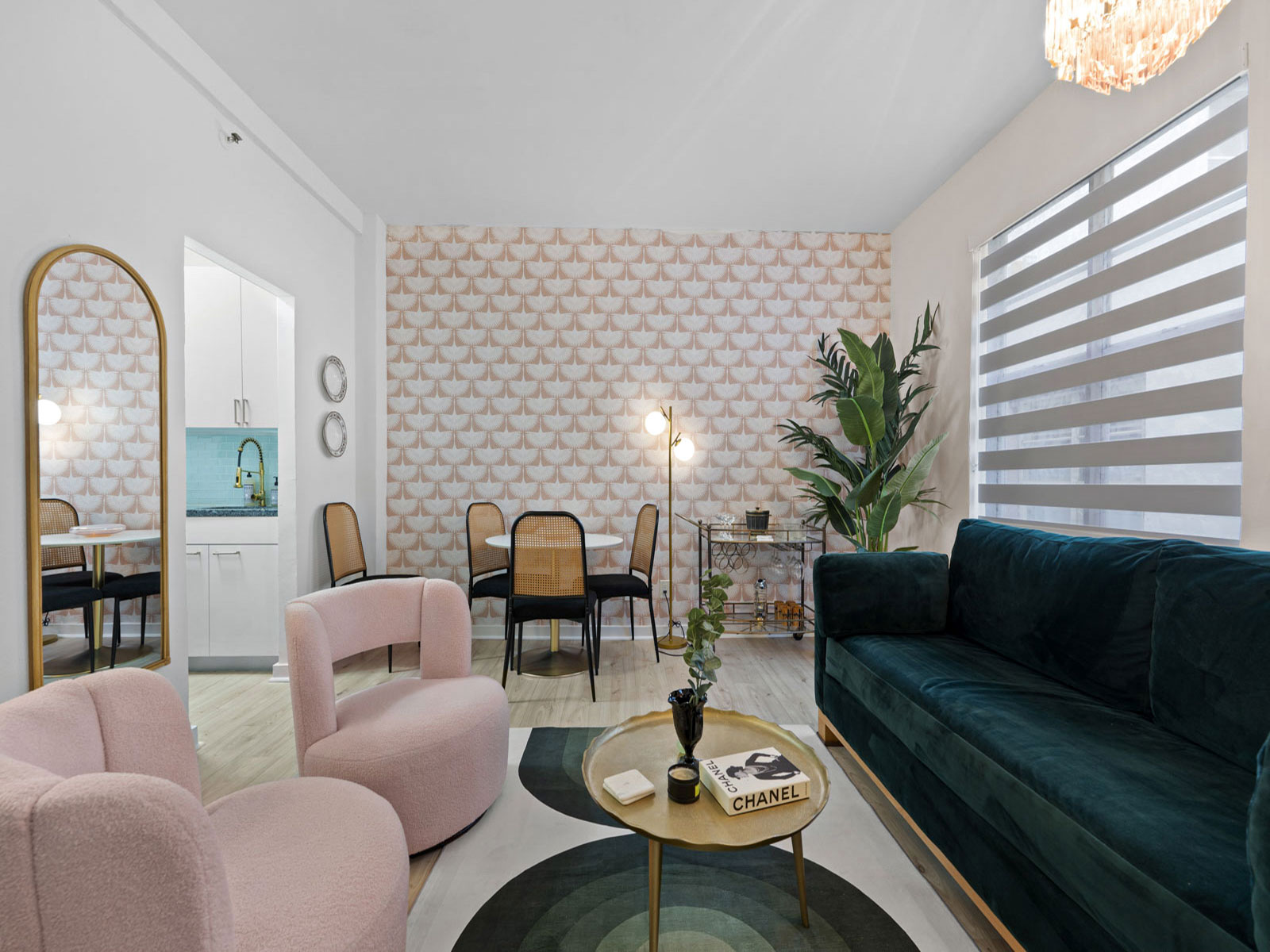 The living room of Unit 1E, with pink armchairs, a green velvet sofa and a fan-patterned feature wall
